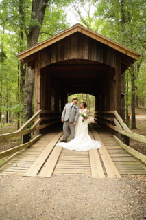 A bride and groom standing on wooden bridge