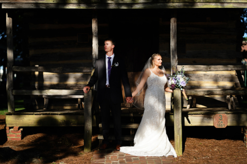 A bride and groom standing near a wooden structure