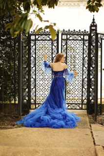 A woman in blue dress opening a gate