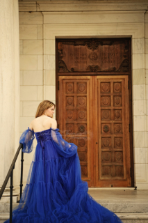 A girl wearing long blue dress in front of a door
