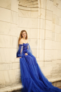 A woman wearing a long blue dress and posing