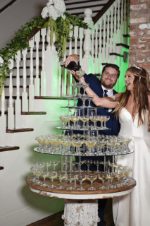 A bride and groom pouring Champagne on a glass tower