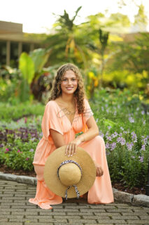 A woman sitting on the floor with flower plants in the background