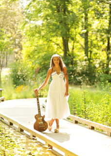 A girl holding a guitar and walking